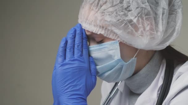 A young doctor prays for the patients health, a surgeon wearing protective gloves and a cap, a medical specialist is going through after the operation — Stock Video