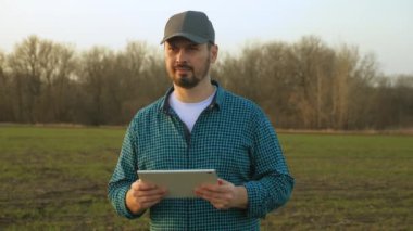 Gün batımında tarla buğdayında tarım yapan çiftçi. Ekokültür çiftliği. Kıdemli çiftçi, işyeri sahibi tarla buğdayındaki tablete bakıyor. Elinde tabletle kıdemli tarım uzmanı. Çiftçi tarım uzmanı eko-ekinleri kontrol ediyor