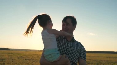 Küçük kız gün batımının parıltısında babasının kollarında güler, aile hayatı kavramı, çocuklu yetişkin bir baba güler, çocuk havada uçar ebeveyniyle eğlenir, şafakta birlikte bir yolculuğa çıkar.