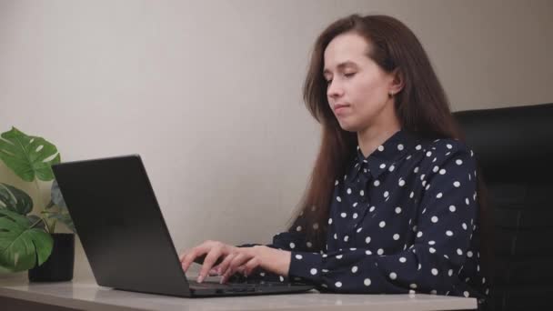 Een volwassen jonge vrouw zit te werken op een laptop in een thuiskantoor, een freelancer op isolatie, een meisje studeert online, een moderne manier van communiceren sociale netwerken, een concept van het leven, 4K, kantoor — Stockvideo