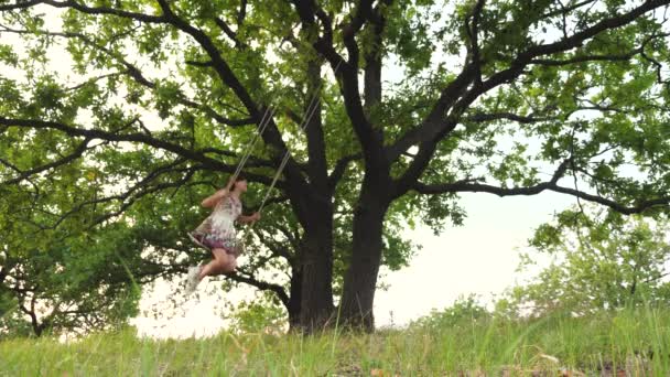 Gelukkig tienermeisje slingeren hoog op een schommel in de lucht, stijgen hoger en vliegen lachen, spelen vlucht, jeugd van een tiener in games op straat, is adembenemend met vreugde en adrenaline — Stockvideo