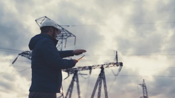 Senior-Elektrotechniker arbeitet mit Tablet in der Nähe von Stromleitungen. Der leitende Elektroingenieur verteilt elektrische Energie. Geschäftsmann Elektriker arbeitet mit elektrischer Energie mit einem Tablet — Stockvideo