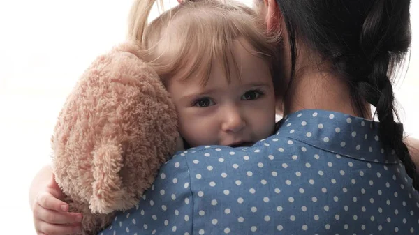A mother calms a small child holding and shaking a teddy bear with a teddy bear, an upset kid is looking for support in a mother s embrace, the concept of family relationships, a woman nanny takes — Stock Photo, Image