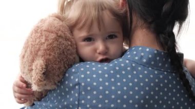 Bir anne kucağında oyuncak ayıyla küçük bir çocuğu sakinleştirir ve sallar, üzgün bir çocuk annesinin kucağında destek arar, aile ilişkileri kavramı, bir kadın dadı...