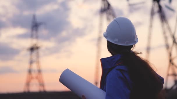 Trabajador de ingeniería eléctrica en silueta de casco trabajando al atardecer cerca de la torre con electricidad. concepto de industria de tecnología energética empresarial. electricista estudiando lectura de documentos sobre estilo de vida — Vídeo de stock