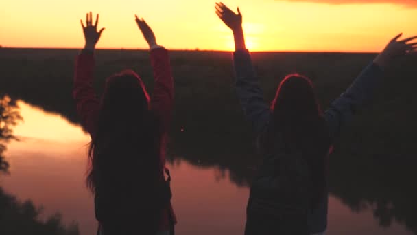 Gelukkige meisjes reizigers met rugzakken op hun schouders springen op en lachen van vreugde, een toeristische cognitieve wandeling, bereiken het doel en succes te bereiken, worden de eerste op het hoogtepunt, het leven van een zwerver op — Stockvideo