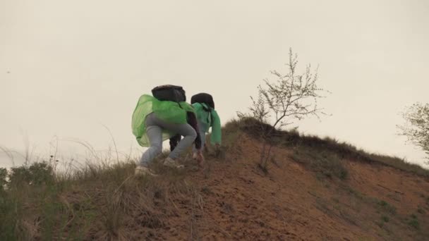 Chicas adultas viajeras suben a la montaña con mochilas en sus hombros, aventura y recreación los fines de semana y vacaciones, un viaje turístico de una chica con un amigo — Vídeos de Stock