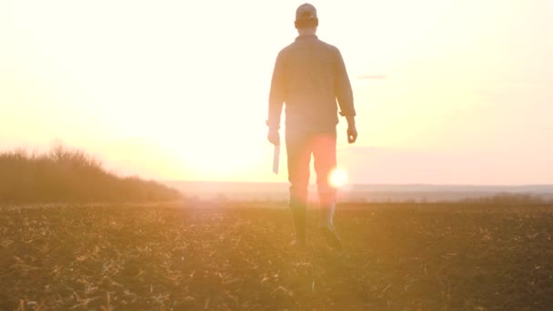 Landbouw. slimme landbouwtechnologie. boer lopen voeten in laarzen met digitale tablet lopen op groen veld van gras bij zonsondergang. landbouwconcept voor landbouwwandelingen — Stockvideo