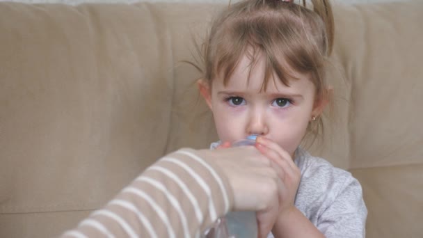 En liten flicka dricker rent renat vatten från en genomskinlig flaska, ett aktivt barn släcker sin törst, ordentligt dricka för hälsan hos babys kropp — Stockvideo