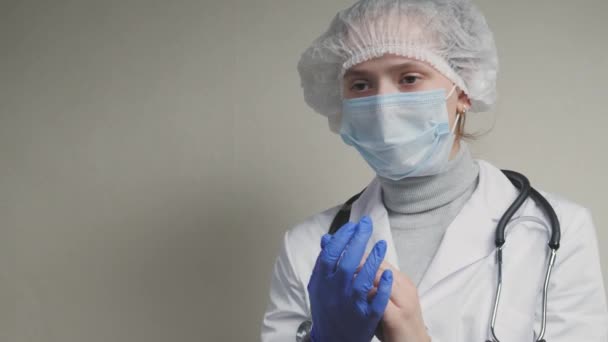 Mulheres médicos cumprimentam uns aos outros com os cotovelos, o médico coloca luvas azuis protetoras em suas mãos, proteção contra o vírus na prevenção de entrar no trato respiratório dos pulmões — Vídeo de Stock
