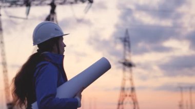 Kask siluetindeki elektrik mühendisi güneş batımında kulenin yanında elektrikle çalışıyor. İş enerjisi teknoloji endüstrisi konsepti. Elektrikçi yaşam tarzı üzerine okuma belgeleri okuyor