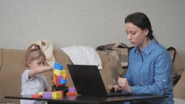 Een freelance vrouw werkt thuis op afstand op een computer met een klein kind, moeder maakt een bestelling in een online winkel via een laptop applicatie, moderne technologieën van gatget systemen in een mensenleven — Stockvideo