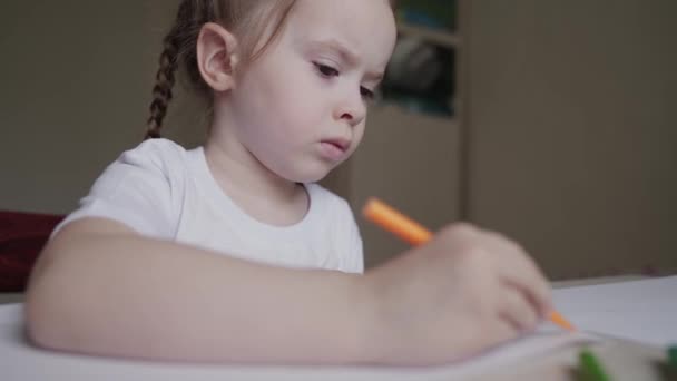 かわいいスマート小学生の女の子の書き方を学ぶ数学の宿題を書いて自宅のテーブルに座って、かわいい小さな就学前の子供はノートを作るだけで勉強し、子供の小学校の教育の概念 — ストック動画