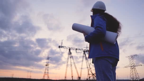 Trabajador de ingeniería eléctrica en silueta de casco trabajando al atardecer cerca de la torre con electricidad. concepto de industria de tecnología energética empresarial. electricista estudiando lectura de documentos sobre estilo de vida — Vídeo de stock