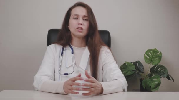 Le médecin accepte un patient malade en ligne à distance via la communication vidéo alors qu'il est assis au bureau à la table, le traitement et les recommandations, prescrire une prescription de médicaments via Internet — Video