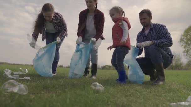 Ein kleines Kind mit seinen Eltern sammelt Müll in einem Park Erholungsgebiet, Gruppenreinigung des Territoriums, Ökologie der Sauberkeit, Sammlung von Plastikflaschen, Müll, Teamarbeit, glückliche Familie und Kind — Stockvideo