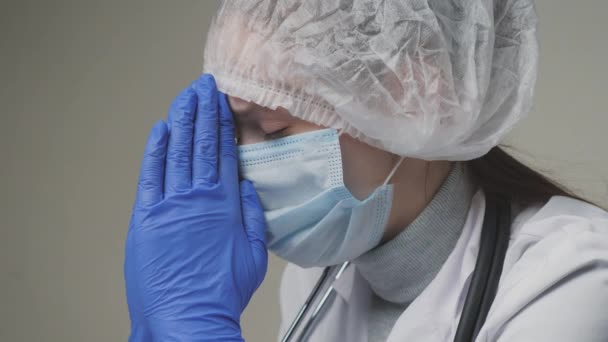 Egy védekező kék maszkos női orvos, egy sapka és egy sztetoszkóp aggódik a műtét után, egy kórház létrehozása a betegek számára, az orvos ideges a betegek egészsége miatt. — Stock videók