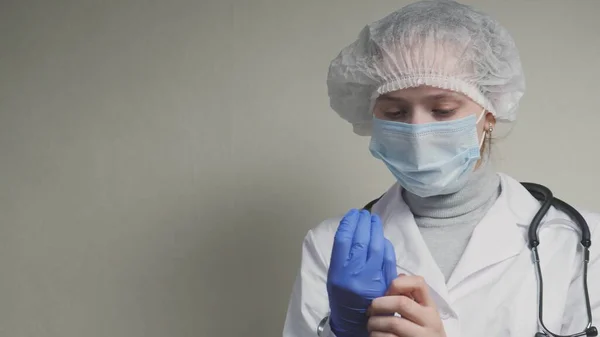 Женщины-врачи приветствуют друг друга локтями, доктор надевает защитные голубые перчатки на руки, защиту от вируса при предотвращении попадания в дыхательные пути легких — стоковое фото