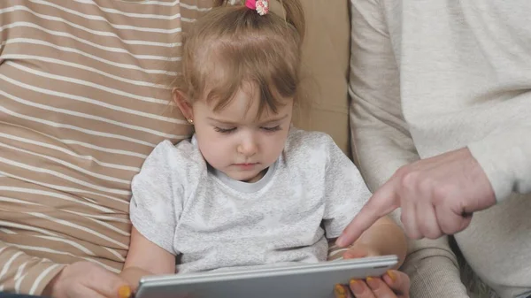 Ребенок с родителями занимается онлайн через приложение гаджета, современное обучение детей, развитие памяти, внимание через планшетный датчик, бизнес-исследования — стоковое фото