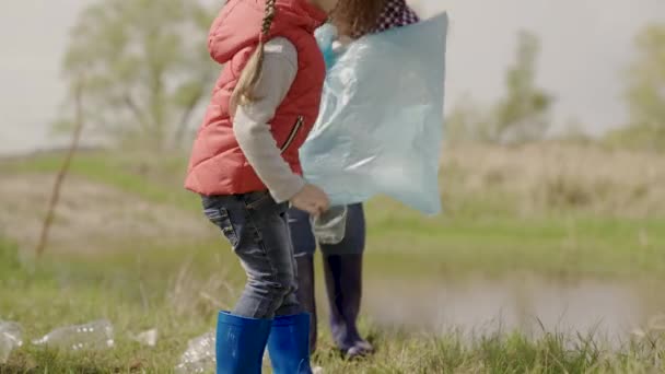 El niño recoge la basura en un equipo de voluntarios sobre temas ambientales, limpia la tierra de la basura, recoge los residuos arrojados a los lugares de descanso, hábitat en peligro — Vídeos de Stock