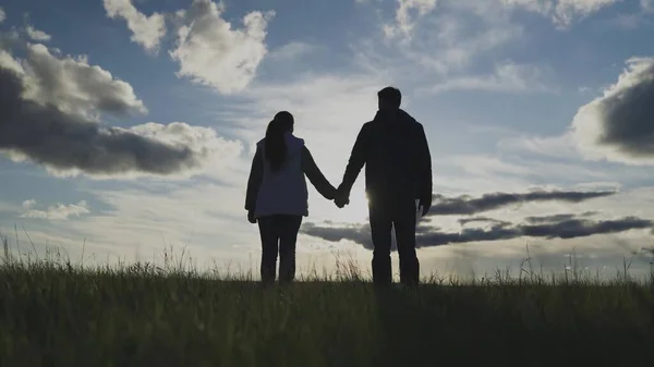 Muž a žena stojí při západu slunce, drží se za ruce, týmová práce, pole — Stock fotografie