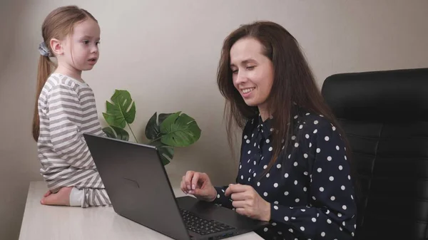 Bizneswoman pracuje na laptopie za pośrednictwem komunikacji wideo online z dzieckiem, freelancer w biurze domu, firma w kwarantannie, dziewczyna z dzieckiem rozmawia przez wyświetlacz komputera — Zdjęcie stockowe