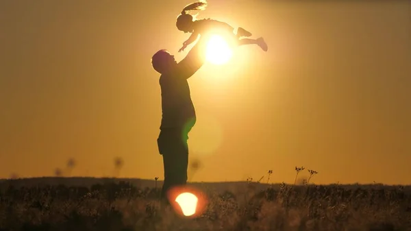 Silhouette Papa wirft glückliche kleine Tochter in den Sonnenuntergang Himmel. Vatertag. Das Kind will über den Boden fliegen. Ein Elternteil mit Kind spielt im Morgengrauen. Familien- und Kindheitskonzept. Kind springt auf — Stockfoto