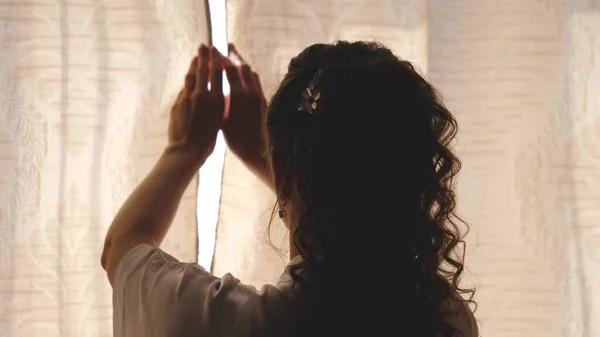 Mãos puxando uma cortina de janela para a luz da manhã quente. Movimento lento. Jovem mulher cortinas de abertura em um quarto. Fecha a porta. Femele mãos abrir cortina de janela de manhã — Fotografia de Stock