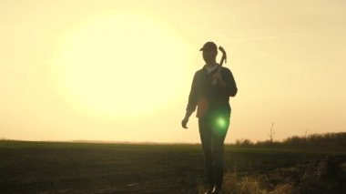 Bir çiftçi gün batımında toprağı kazmak için lastik çizmeli bir kürekle tarlada yürüyor. Tarım, arazi, sebze, meyve, tohum ekme, kazı sezonu.