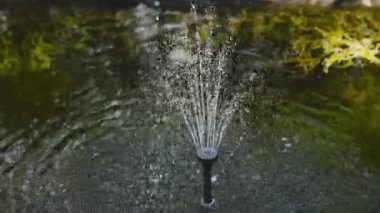 Bahçe için suyla süslemenin dekoratif süslemesi, jet spreyi ve yavaş çekimde bir damla su, yerin altından akan sıvı su, bir bahçe çeşmesi.