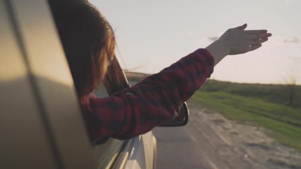 Het meisje reist met haar hand uit het raam van de auto en vangt de wind in de schittering van de zon, neemt een lange weg op een zakenreis, een gelukkige man die met de wind speelt, het is tijd om vrij te dromen — Stockvideo