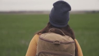 Güzel vadide sırt çantasıyla gezen mutlu, aktif hippi kız, yeşil tarlada milenyum kadını, yürüyüş gezisi, yürüyüş parkuru, hafta sonu gezisi.