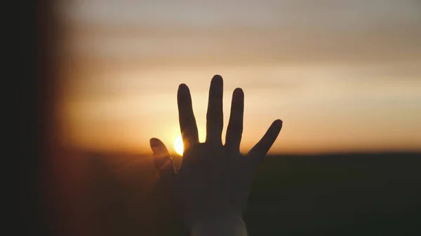Reiken naar de zon, gelukkig meisje bij zonsondergang, zonlicht op haar hand, zonnestelsel ster, gelukkig familie concept, aanraken van een droom, vragen om hulp van God, natuurlijk fenomeen — Stockfoto