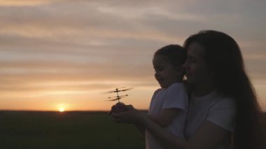 Anne ile çocuk gün batımında gökyüzüne oyuncak bir helikopter fırlatıyor, çocuk düşünmenin gelişimi için eğitici oyuncaklar, mutlu aile kavramı, anneye özen gösteren çocuk, takım çalışması