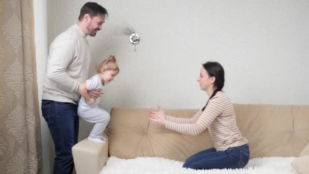 Los padres juegan con el niño en el interior de casa, el concepto de una familia feliz, el pequeño bebé se divierte con su padre y su madre, una infancia feliz, el amor en la crianza de un niño, el trabajo en equipo, vivir un pleno derecho — Vídeos de Stock