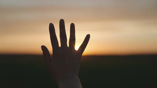 Reiken naar de zon, gelukkig meisje bij zonsondergang, zonlicht op haar hand, zonnestelsel ster, gelukkig familie concept, aanraken van een droom, vragen om hulp van God, natuurlijk fenomeen — Stockfoto