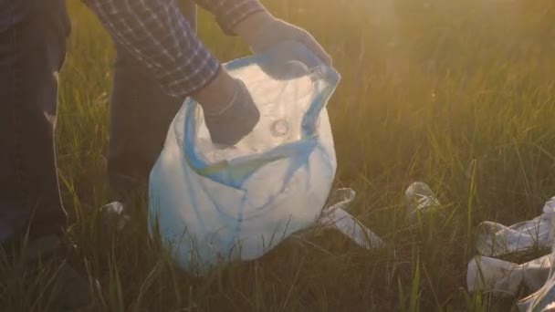 Mano maschile raccoglie rifiuti in un sacchetto della spazzatura, volontariato per proteggere la natura, mantenere un pianeta pulito rotondo, concetto di famiglia felice, sbarazzarsi di rifiuti di plastica, vivere in un ambiente pulito — Video Stock