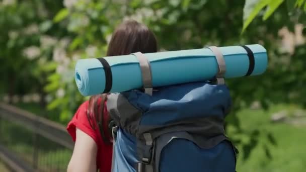 Young millennial girl travels with backpack and tourist rug, bright day in life, happy vacation concept, nature vacation on tourist road, looking for adventure on vacation, traveler concept — Stock Video