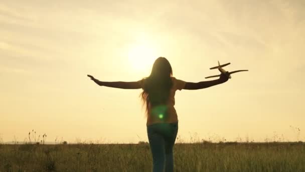 Dziecko marzy o byciu pilotem samolotu lecącego na niebie ku słońcu, dziecko biegnie w stronę zachodzącego słońca, uwielbia biegać w naturze, dziewczyna bawi się na świeżym powietrzu, czuje swobodę gry — Wideo stockowe