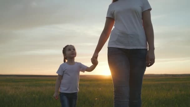 Uma criança pequena segura a mão da mãe ao pôr do sol, amor materno e cuidado com sua filha, tocar o sonho da mãe, o conceito de uma vida familiar feliz, a criança toca o pai com a mão. — Vídeo de Stock