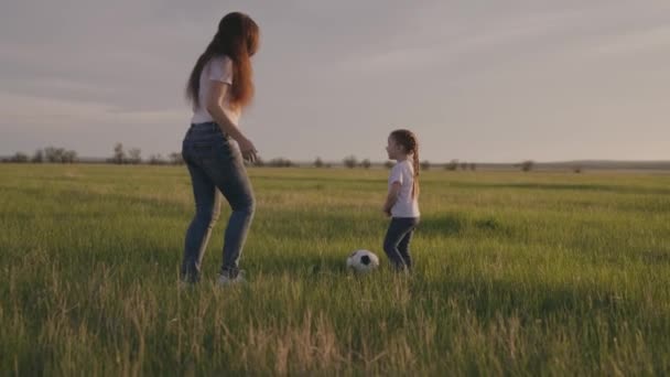 Klein kind rent over het groene voetbalveld voetballen bij zonsondergang in de lucht, kind schopt de bal en haalt hem in, het concept van een gelukkig kinderleven, actieve gezonde baby — Stockvideo