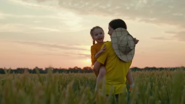 Moeder boer met een klein kind in haar armen loopt door het veld met tarwe, gelukkig gezin, agronomische vrouw, bedrijfslandbouw, gewassen verbouwen in de open lucht, rijpen op de grond — Stockvideo