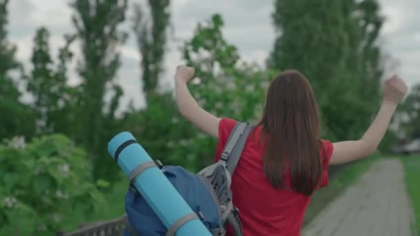 Chica joven millennial viaja con mochila y alfombra turística, día brillante en la vida, feliz concepto de vacaciones, vacaciones en la naturaleza en la carretera turística, en busca de aventura en vacaciones, concepto de viajero — Vídeos de Stock