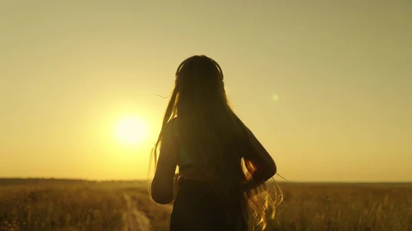 Happy girl runs in headphones at sunset, an active lifestyle for losing weight and maintaining a slim figure, a woman striving for the dream of being the first, preparing for a running competition — Stock Photo, Image