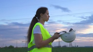 Bir elektrikçi kafasına koruyucu bir kask, kablolarda voltaj altında bir elektrik santrali, mühendislik çalışmalarının enerjisi, elektrik akımı teknolojisi, elektrik işi konsepti koyar.