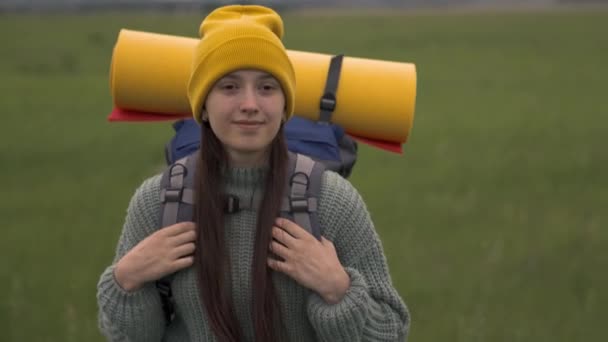 Felice ragazza hipster attiva con lo zaino sulla schiena viaggiare nella bellissima valle, donna millenaria sul campo verde, viaggi escursionistici, sentiero escursionistico, weekend ricreativo all'aperto — Video Stock