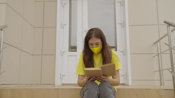 Ein Schulmädchen in Maske liest in der Schule ein Buch, Schutz vor Coronavirus, Covid-19-Pandemie, Luftfilterung durch Maskenfilter, moderne Bildung für Jugendliche — Stockvideo