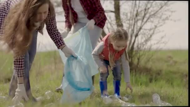 Kleines Kind mit Familie sammelt Müll im Müllpark, glückliche Familie, ehrenamtliches Team zur Umweltsanierung, Umweltverschmutzung, Plastikverschmutzung und Umweltschutzkonzept — Stockvideo