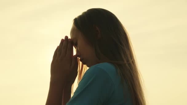 Une fille musulmane prie dans l'éblouissement du soleil dans le ciel, un petit adolescent croit en la bonté, demande pardon du ciel, éduque un enfant à la religion, demande de bonnes choses dans la vie, rêve d'enfant — Video