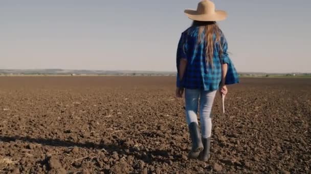 Agricoltura, un agricoltore in stivali di gomma cammina sul terreno arato, a riposo un appezzamento di terreno dopo la raccolta, un agronomo controlla il terreno con una tavoletta in mano, agribusiness dei campi nel — Video Stock